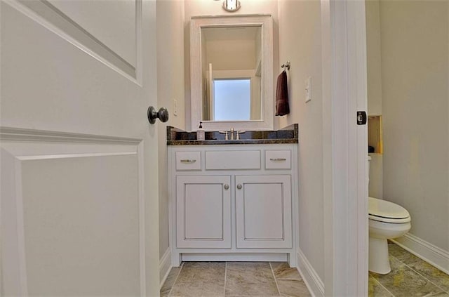 bathroom featuring vanity, baseboards, and toilet