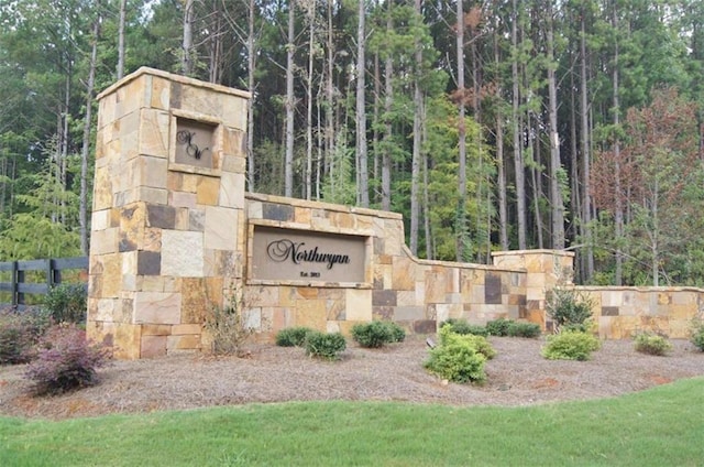 community / neighborhood sign featuring a view of trees