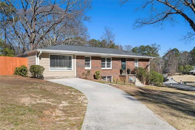 ranch-style home with a front yard, brick siding, and fence