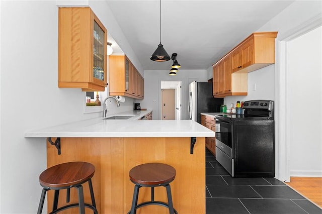 kitchen featuring stainless steel appliances, a peninsula, a sink, light countertops, and glass insert cabinets