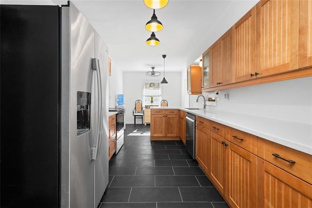 kitchen featuring appliances with stainless steel finishes, decorative light fixtures, a peninsula, light countertops, and a sink