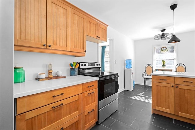 kitchen featuring hanging light fixtures, dark tile patterned floors, stainless steel electric range, and light countertops