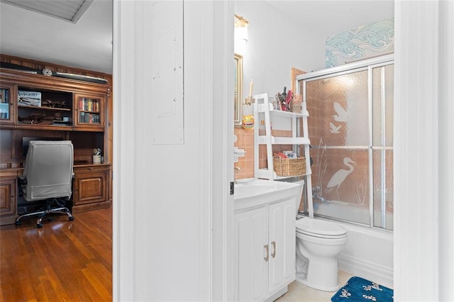 full bath with enclosed tub / shower combo, toilet, wood finished floors, and vanity