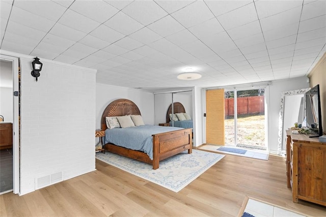 bedroom featuring light wood-style floors, access to exterior, visible vents, and crown molding