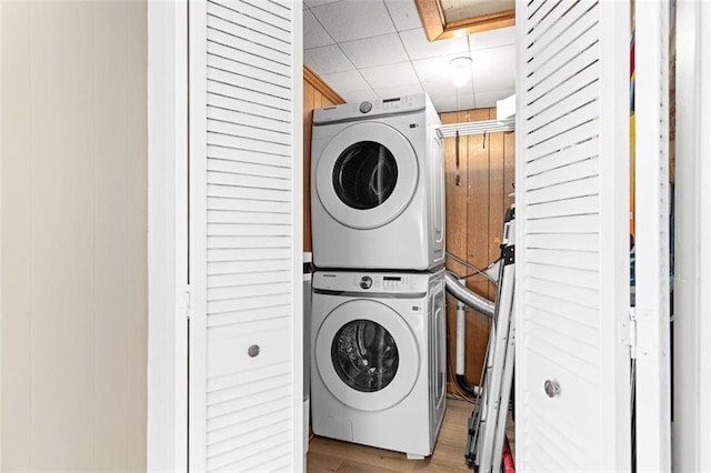 laundry area featuring laundry area, light wood finished floors, and stacked washer and clothes dryer