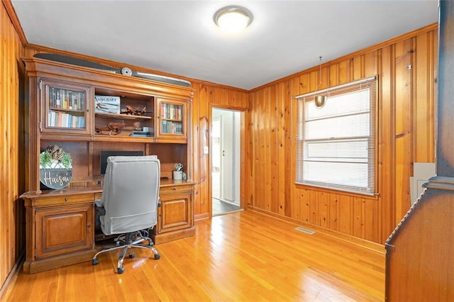 office space with wood walls, light wood-type flooring, visible vents, and crown molding