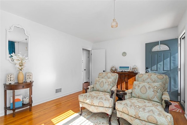 living area with wood finished floors, visible vents, and baseboards