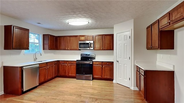 514 Jadetree Ln, Atlanta, GA 30349 - kitchen with stainless steel appliances, a sink, light wood-type flooring, a textured ceiling, and light countertops