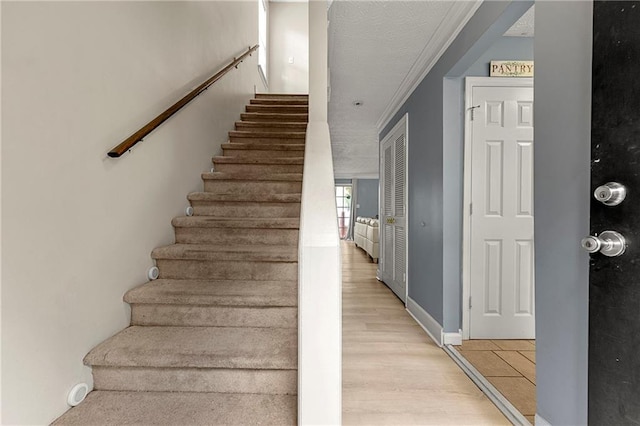 stairs with hardwood / wood-style floors, a textured ceiling, and crown molding