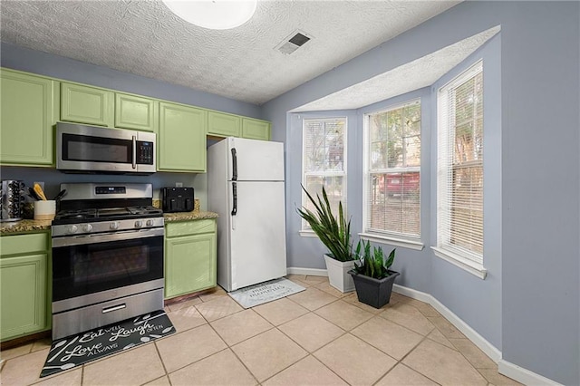 kitchen featuring green cabinets, stainless steel appliances, a textured ceiling, and light tile patterned floors