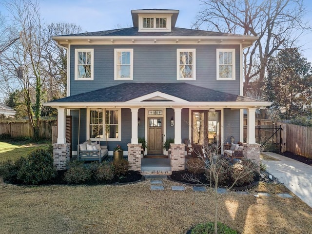 traditional style home featuring a porch, a front lawn, and fence