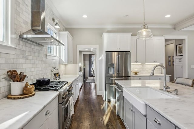 kitchen with a sink, premium appliances, crown molding, and wall chimney range hood