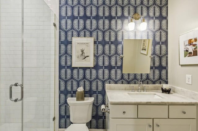 bathroom featuring a shower stall, wallpapered walls, toilet, and vanity