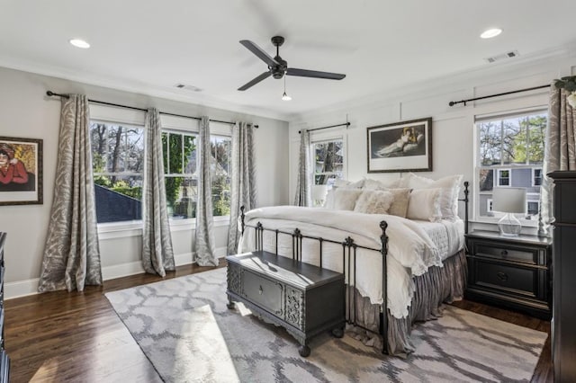 bedroom with crown molding, wood finished floors, visible vents, and baseboards