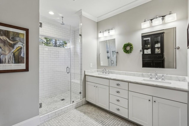 bathroom with double vanity, a shower stall, ornamental molding, and a sink