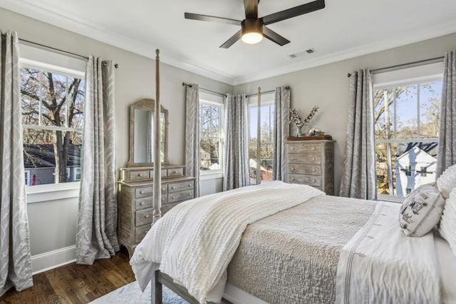 bedroom with wood finished floors, visible vents, baseboards, ceiling fan, and crown molding