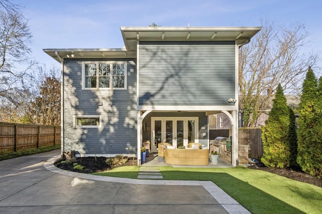 back of property featuring a lawn, fence, french doors, an outdoor hangout area, and a patio area