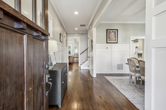 foyer entrance with visible vents, ornamental molding, dark wood-style floors, a decorative wall, and stairs