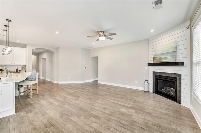 242 Aspen Way, Dallas, GA 30157 - unfurnished living room with ceiling fan, a large fireplace, arched walkways, light wood-type flooring, and recessed lighting