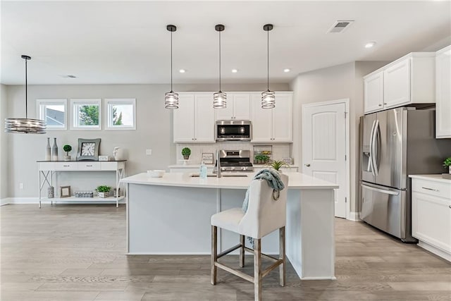 242 Aspen Way, Dallas, GA 30157 - kitchen with appliances with stainless steel finishes, light countertops, tasteful backsplash, light wood-style flooring, and a kitchen island with sink