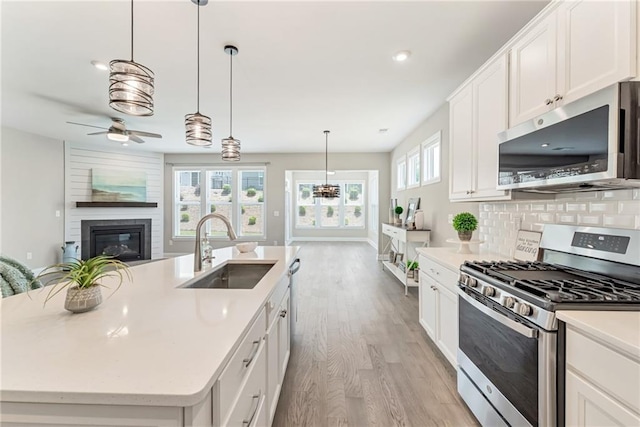 242 Aspen Way, Dallas, GA 30157 - kitchen with stainless steel appliances, open floor plan, light wood finished floors, a glass covered fireplace, and ceiling fan