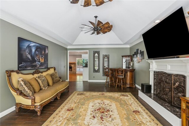 living area with ceiling fan, wood finished floors, baseboards, a fireplace, and crown molding