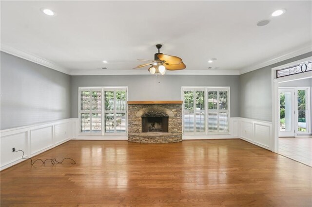 unfurnished living room with plenty of natural light, a stone fireplace, ceiling fan, recessed lighting, and crown molding