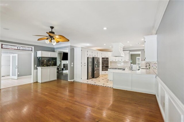unfurnished living room featuring a sink, a ceiling fan, crown molding, light wood-type flooring, and recessed lighting