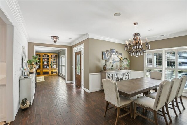 dining space featuring a chandelier, ornamental molding, dark wood finished floors, and baseboards