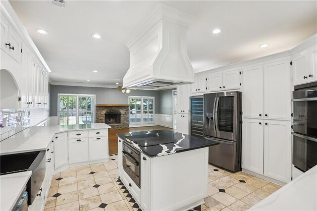 kitchen featuring black appliances, a fireplace, white cabinetry, recessed lighting, and backsplash