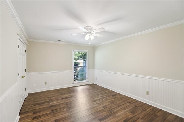 empty room featuring wainscoting, ceiling fan, dark wood-type flooring, and crown molding