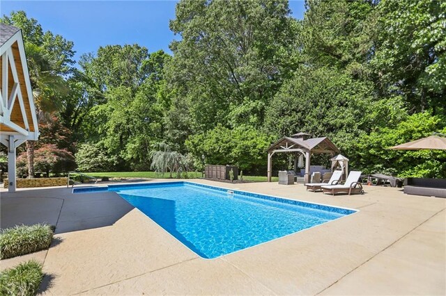 swimming pool featuring a gazebo, a patio, an outdoor hangout area, and view of wooded area