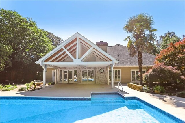 rear view of property featuring a patio, an outdoor pool, french doors, and a chimney