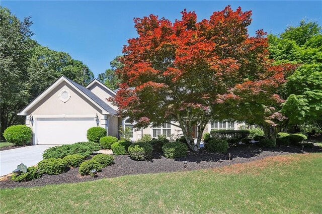 obstructed view of property featuring an attached garage, concrete driveway, a front yard, and stucco siding