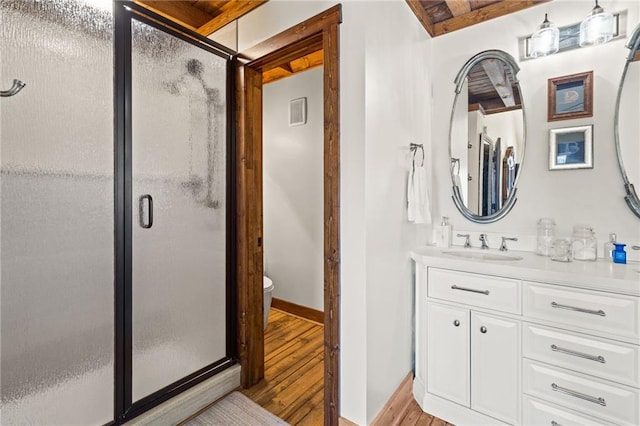 bathroom featuring baseboards, toilet, a stall shower, wood finished floors, and vanity