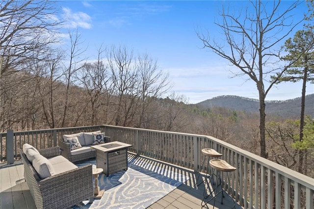 wooden deck with a mountain view, a view of trees, and outdoor lounge area