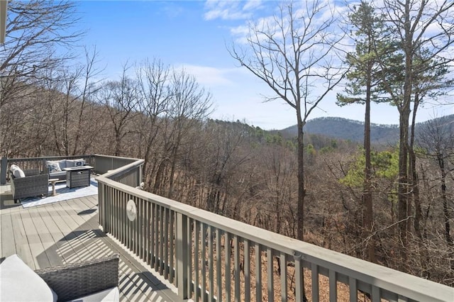 deck with a mountain view, an outdoor hangout area, and a view of trees