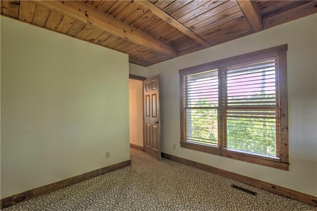 carpeted spare room with beamed ceiling, baseboards, visible vents, and wooden ceiling