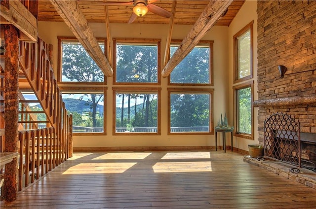 living room with a fireplace, wood ceiling, light hardwood / wood-style floors, ceiling fan, and a towering ceiling