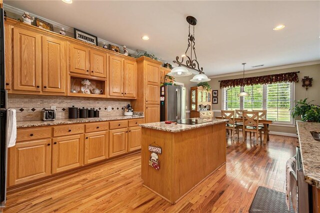 kitchen with pendant lighting, light stone counters, a center island, and stainless steel fridge