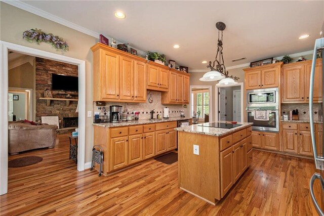 kitchen with light stone counters, a kitchen island, decorative light fixtures, light wood-type flooring, and crown molding