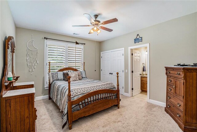 bedroom with a closet, ensuite bath, ceiling fan, and light colored carpet