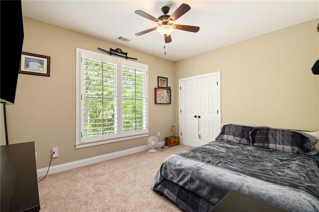 bedroom with light carpet, ceiling fan, and a closet