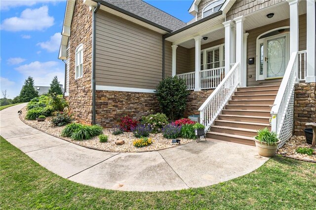 doorway to property with a lawn and covered porch