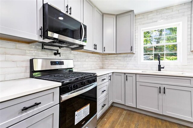 kitchen with gray cabinetry, backsplash, stainless steel appliances, and dark hardwood / wood-style flooring