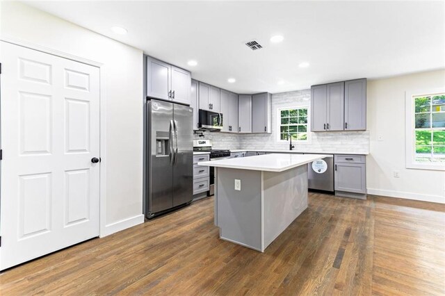 kitchen featuring stainless steel appliances, dark hardwood / wood-style floors, gray cabinets, and a kitchen island