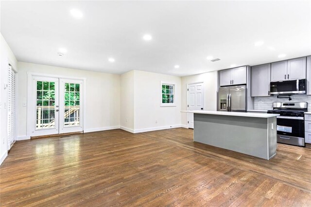 kitchen featuring gray cabinetry, backsplash, stainless steel appliances, dark hardwood / wood-style floors, and a center island