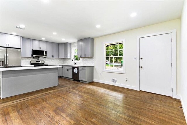 kitchen featuring sink, tasteful backsplash, gray cabinetry, appliances with stainless steel finishes, and dark hardwood / wood-style flooring