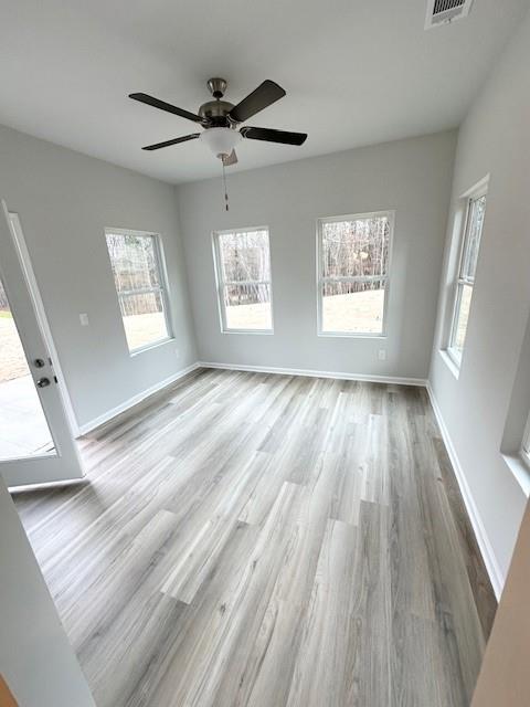 unfurnished room featuring visible vents, light wood-style flooring, and baseboards