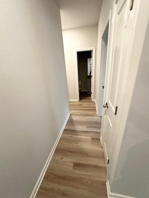 hallway featuring light wood finished floors and baseboards